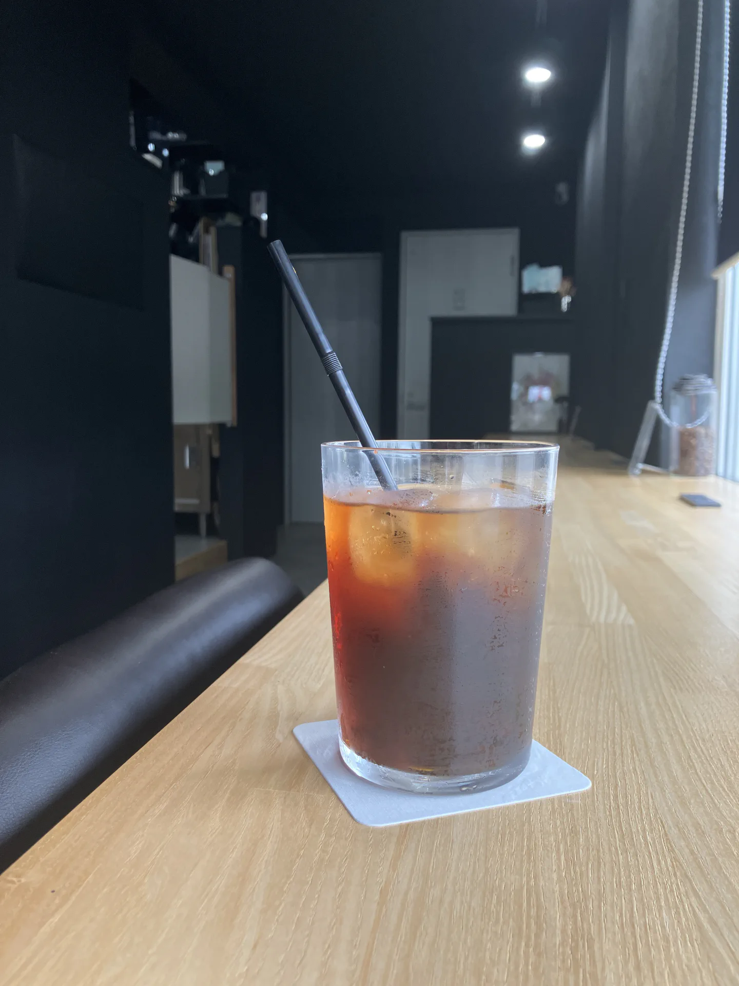 黒い店内の木のカウンターに置かれたアイスコーヒー